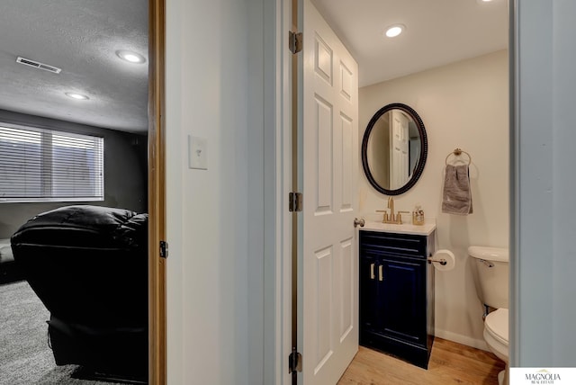 bathroom with visible vents, toilet, a textured ceiling, ensuite bath, and wood finished floors