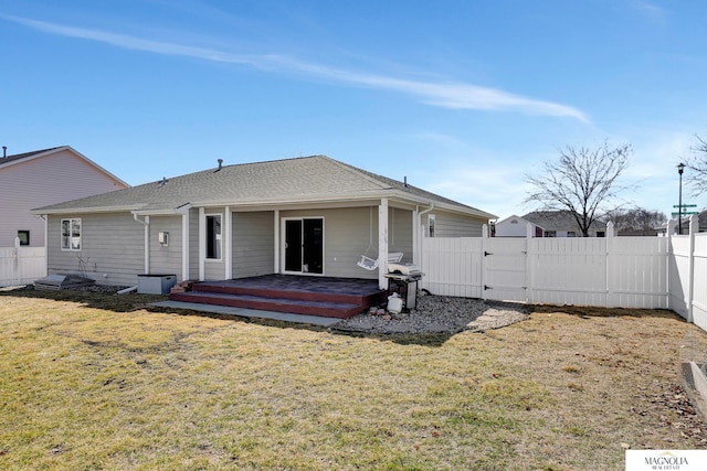 rear view of property featuring a gate, fence, and a yard