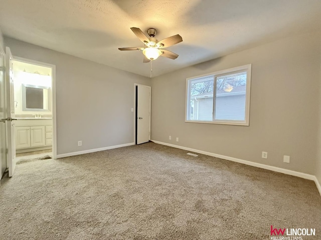 unfurnished bedroom with carpet, a sink, connected bathroom, and baseboards