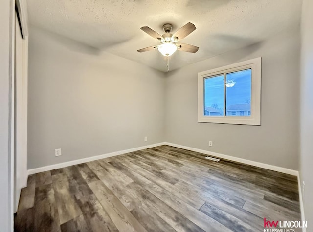 unfurnished room featuring dark wood finished floors, visible vents, ceiling fan, a textured ceiling, and baseboards