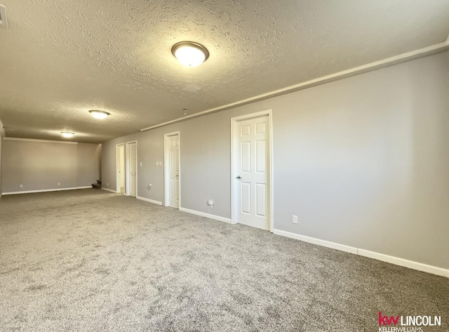 carpeted spare room with a textured ceiling and baseboards