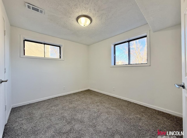 carpeted empty room with a healthy amount of sunlight, baseboards, visible vents, and a textured ceiling