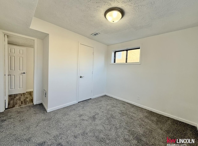 unfurnished bedroom featuring carpet floors, visible vents, a textured ceiling, and baseboards