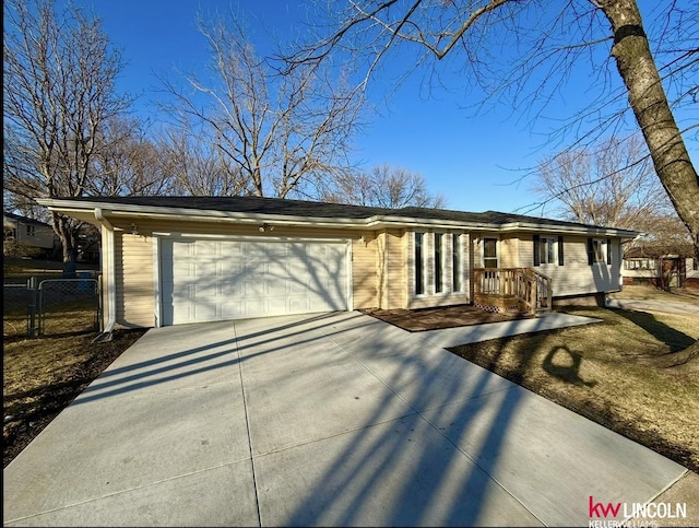 ranch-style house featuring a garage, concrete driveway, and fence