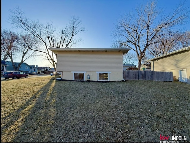 view of home's exterior featuring a lawn and fence