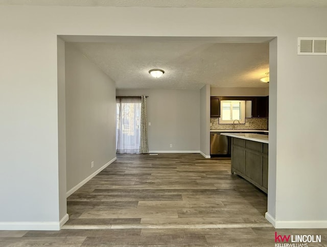 interior space featuring visible vents, a textured ceiling, baseboards, and wood finished floors