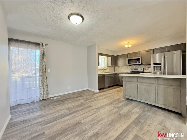 kitchen featuring appliances with stainless steel finishes, plenty of natural light, light countertops, and light wood-style floors