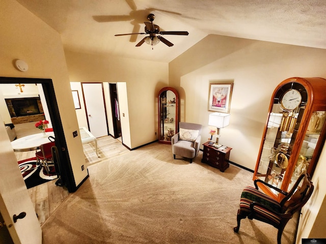 sitting room featuring carpet, a fireplace, lofted ceiling, a ceiling fan, and baseboards