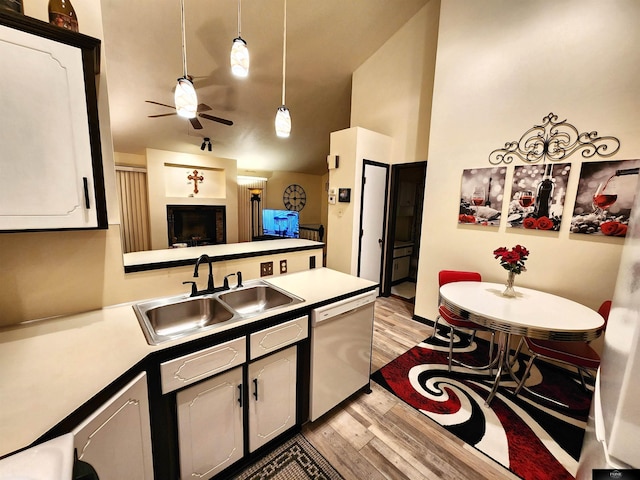 kitchen with light wood-style flooring, a peninsula, white dishwasher, white cabinetry, and a sink