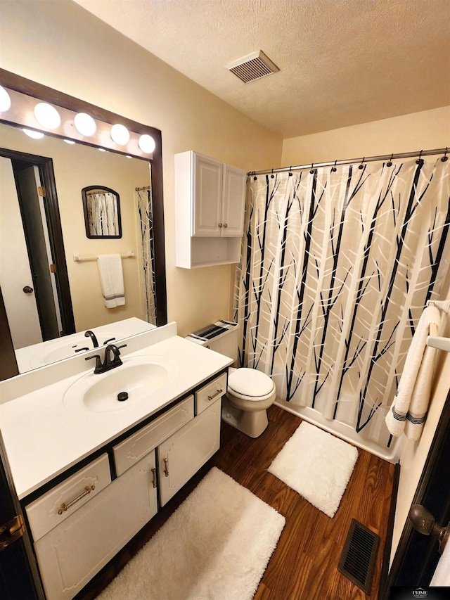 bathroom with visible vents, a textured ceiling, toilet, and wood finished floors