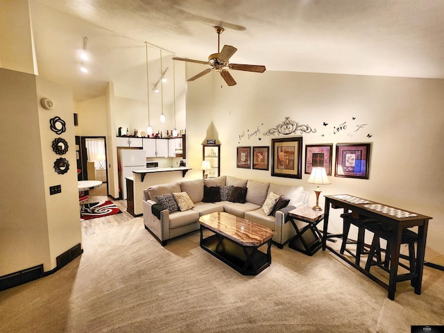 living area featuring baseboards, light colored carpet, ceiling fan, high vaulted ceiling, and bar area