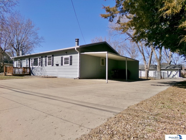 rear view of house featuring a wooden deck, a carport, and concrete driveway