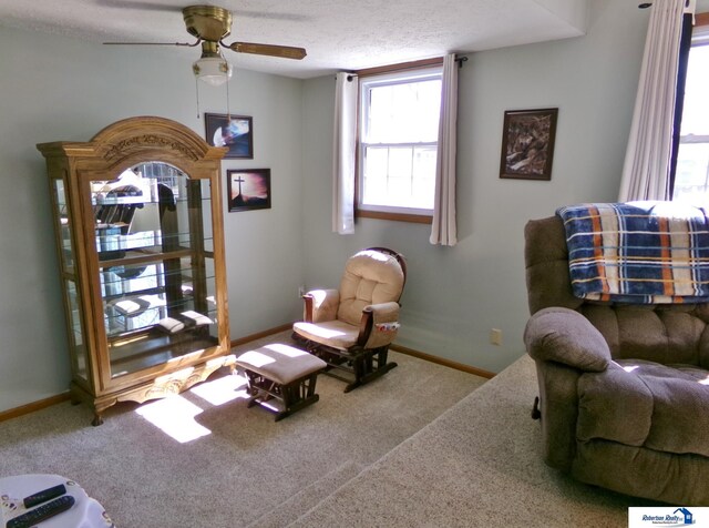 living area with baseboards, a textured ceiling, ceiling fan, and carpet flooring