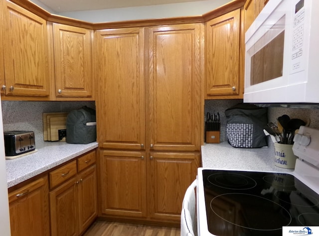 kitchen featuring range with electric stovetop, white microwave, tasteful backsplash, and light countertops