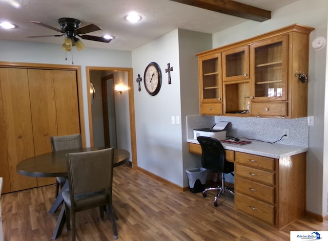 office featuring baseboards, wood finished floors, a ceiling fan, and built in study area