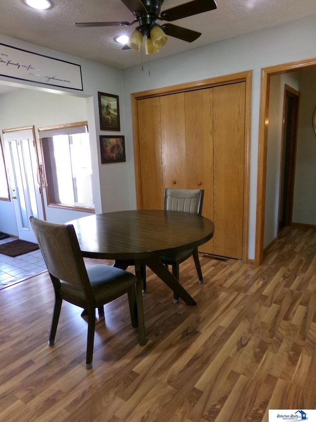 dining space featuring a textured ceiling, light wood-type flooring, and ceiling fan