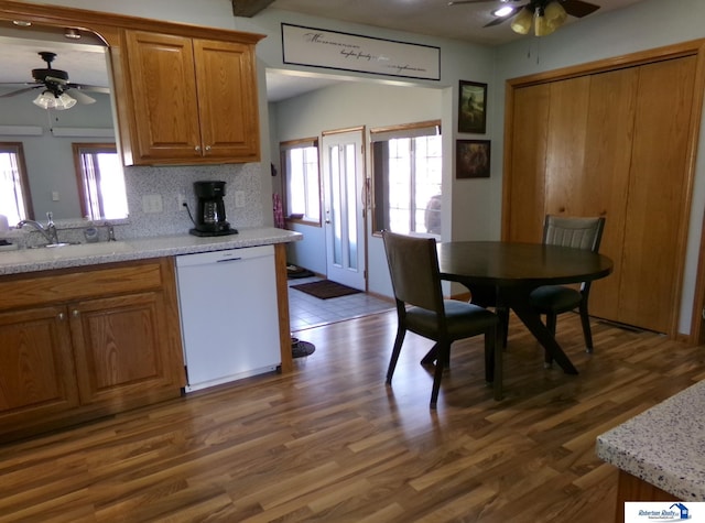 kitchen with a sink, decorative backsplash, light countertops, ceiling fan, and dishwasher