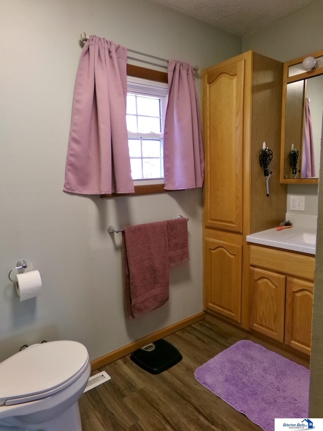 bathroom with visible vents, baseboards, toilet, and wood finished floors