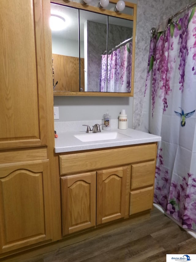 full bath with curtained shower, vanity, and wood finished floors