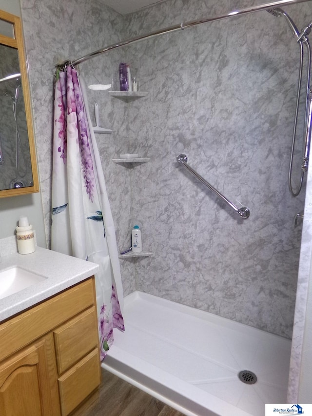 bathroom featuring a shower stall, vanity, and wood finished floors