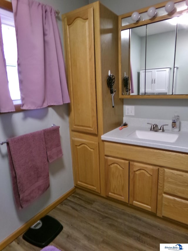 bathroom with vanity, wood finished floors, and baseboards