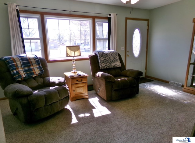 living room featuring visible vents, carpet floors, baseboards, and a ceiling fan