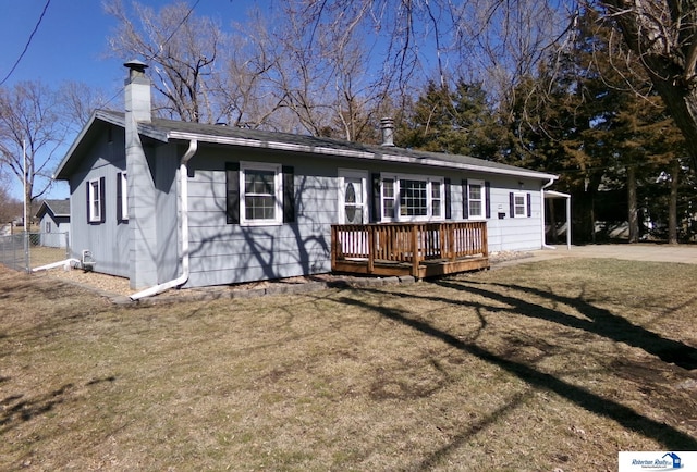 view of front facade with a front lawn, fence, a chimney, and a wooden deck