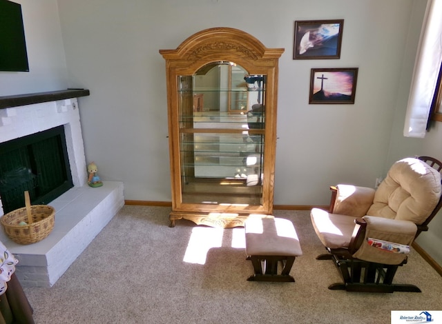 living area featuring carpet flooring, a fireplace with raised hearth, and baseboards