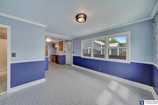 empty room featuring wainscoting and crown molding