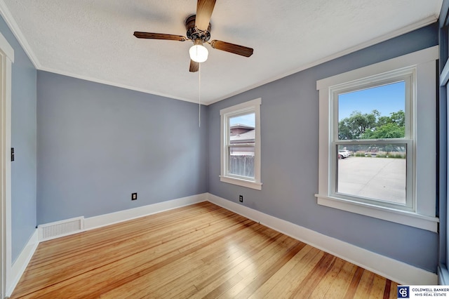 unfurnished room featuring visible vents, light wood-type flooring, baseboards, and ornamental molding