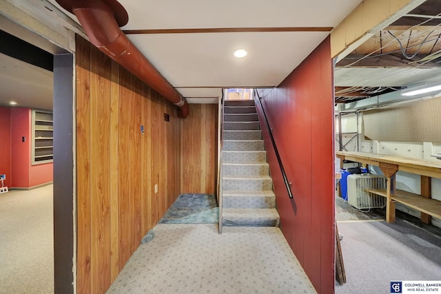 stairway featuring carpet and wood walls