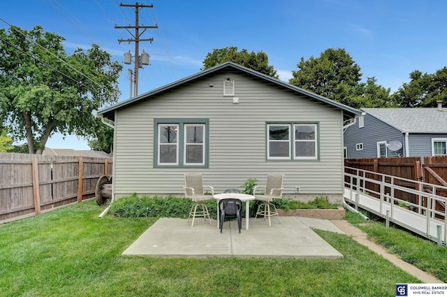 rear view of property featuring a yard, a patio area, and a fenced backyard