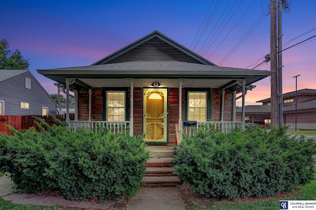 view of front of property with fence, covered porch, and roof with shingles