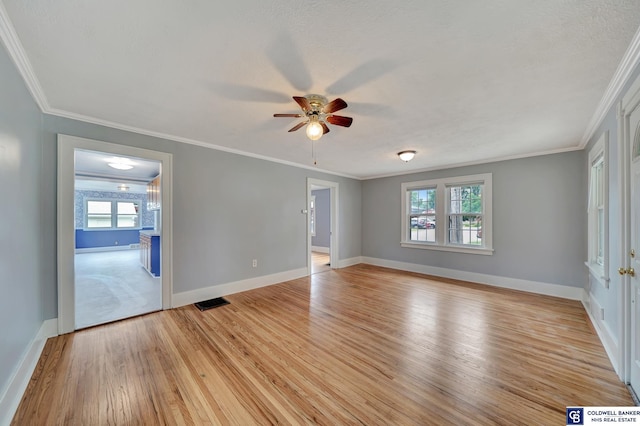 empty room featuring visible vents, baseboards, light wood-style floors, and ornamental molding