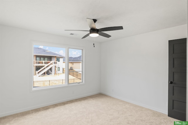 carpeted spare room featuring visible vents, baseboards, and a ceiling fan