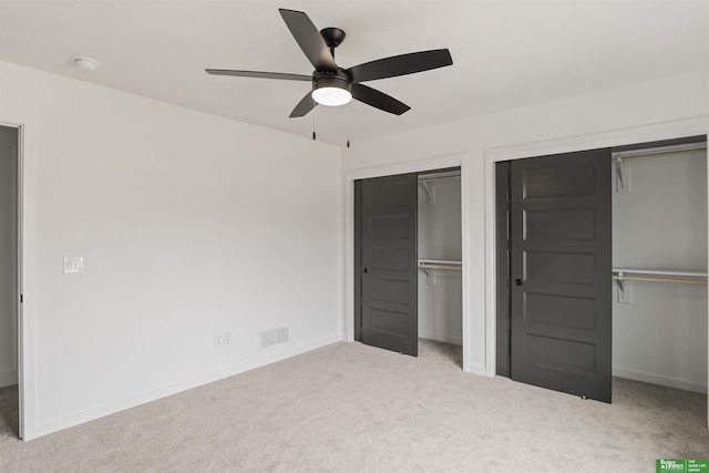 unfurnished bedroom featuring carpet floors, two closets, visible vents, a ceiling fan, and baseboards