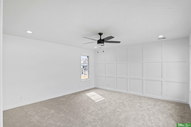 carpeted spare room with recessed lighting, visible vents, a decorative wall, a ceiling fan, and baseboards