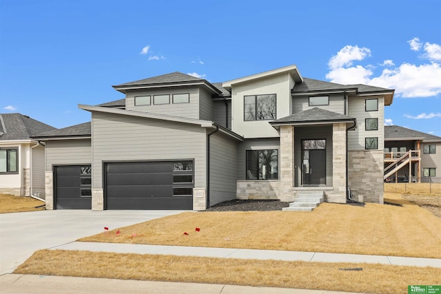 prairie-style house featuring concrete driveway, stone siding, an attached garage, and a shingled roof