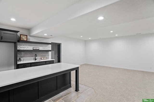 kitchen featuring open shelves, recessed lighting, light countertops, light carpet, and a sink