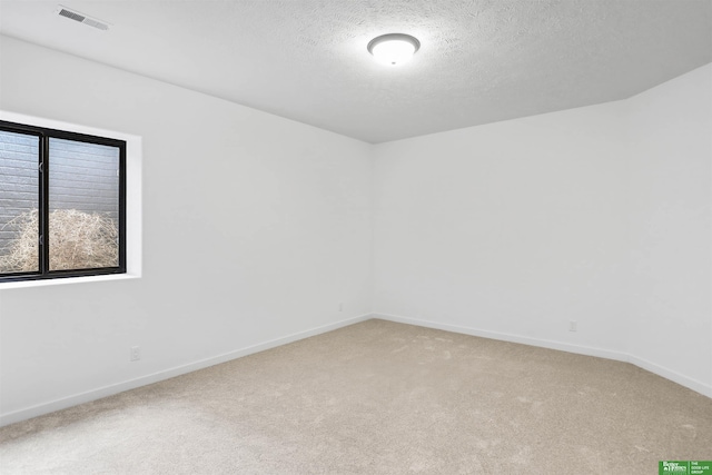 empty room with light carpet, baseboards, visible vents, and a textured ceiling