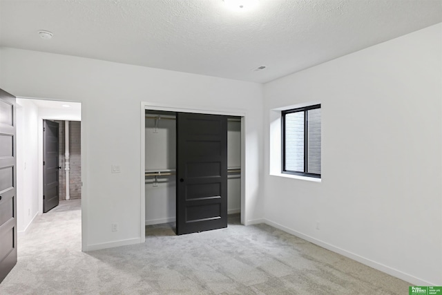 unfurnished bedroom featuring a textured ceiling, a closet, carpet, and baseboards