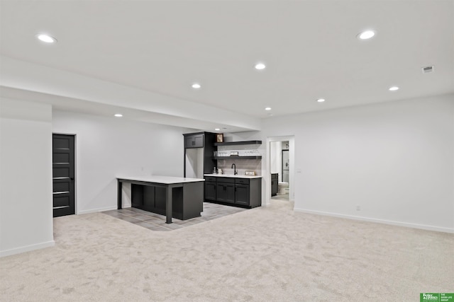 kitchen featuring light countertops, light colored carpet, a sink, and recessed lighting