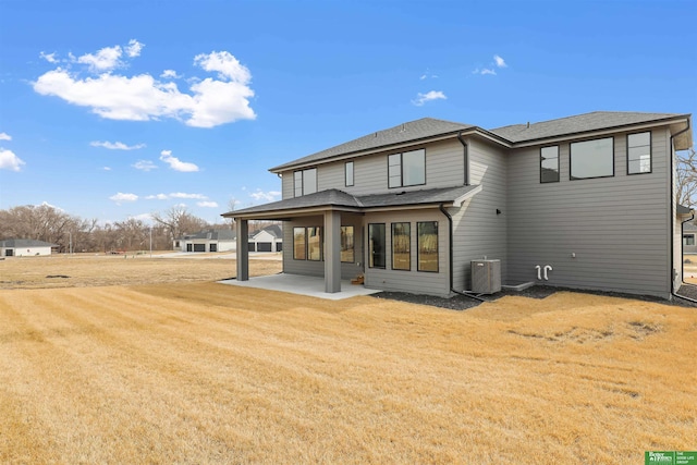 rear view of property with a patio, a yard, roof with shingles, and central air condition unit