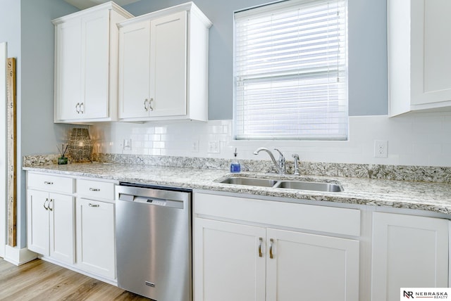 kitchen featuring a sink, white cabinetry, stainless steel dishwasher, light wood-type flooring, and decorative backsplash