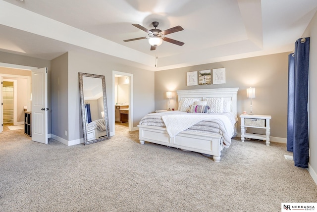 carpeted bedroom with baseboards, a tray ceiling, ceiling fan, and connected bathroom