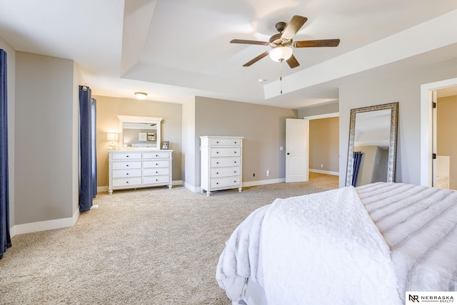 carpeted bedroom with ceiling fan, a raised ceiling, and baseboards