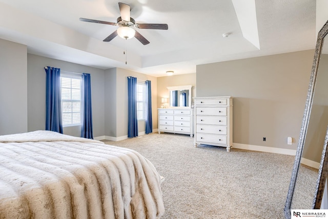 bedroom with light carpet, ceiling fan, baseboards, and a raised ceiling