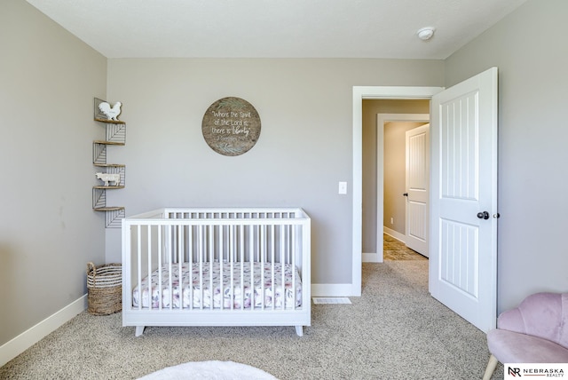 bedroom featuring a nursery area, baseboards, and carpet flooring