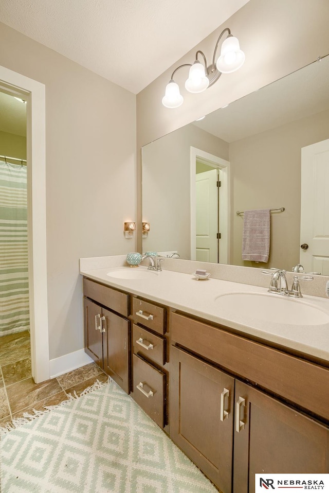 full bath featuring a sink, baseboards, and double vanity