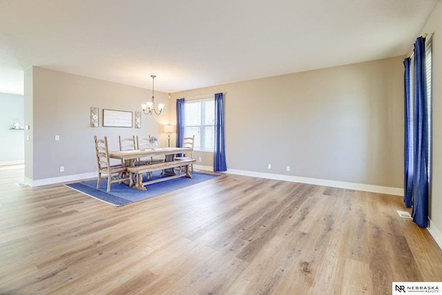 dining room featuring baseboards, light wood-type flooring, visible vents, and an inviting chandelier